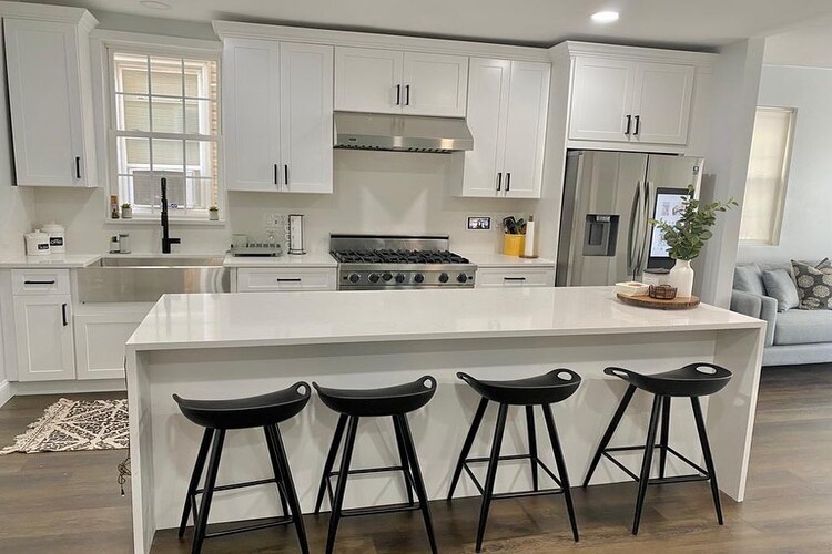 a white themed kitchen area with four black chairs
