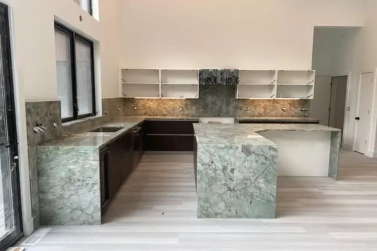 an empty kitchen with a grey marble countertop